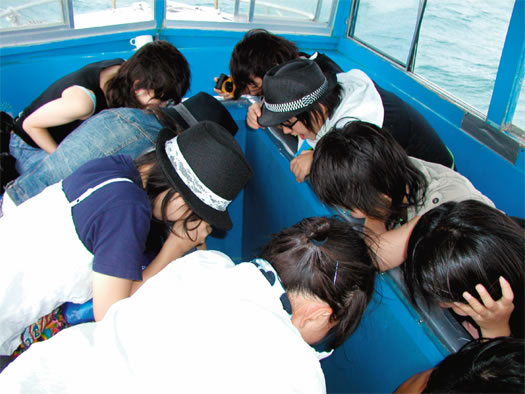 グラスボートから海中をのぞき込む生徒